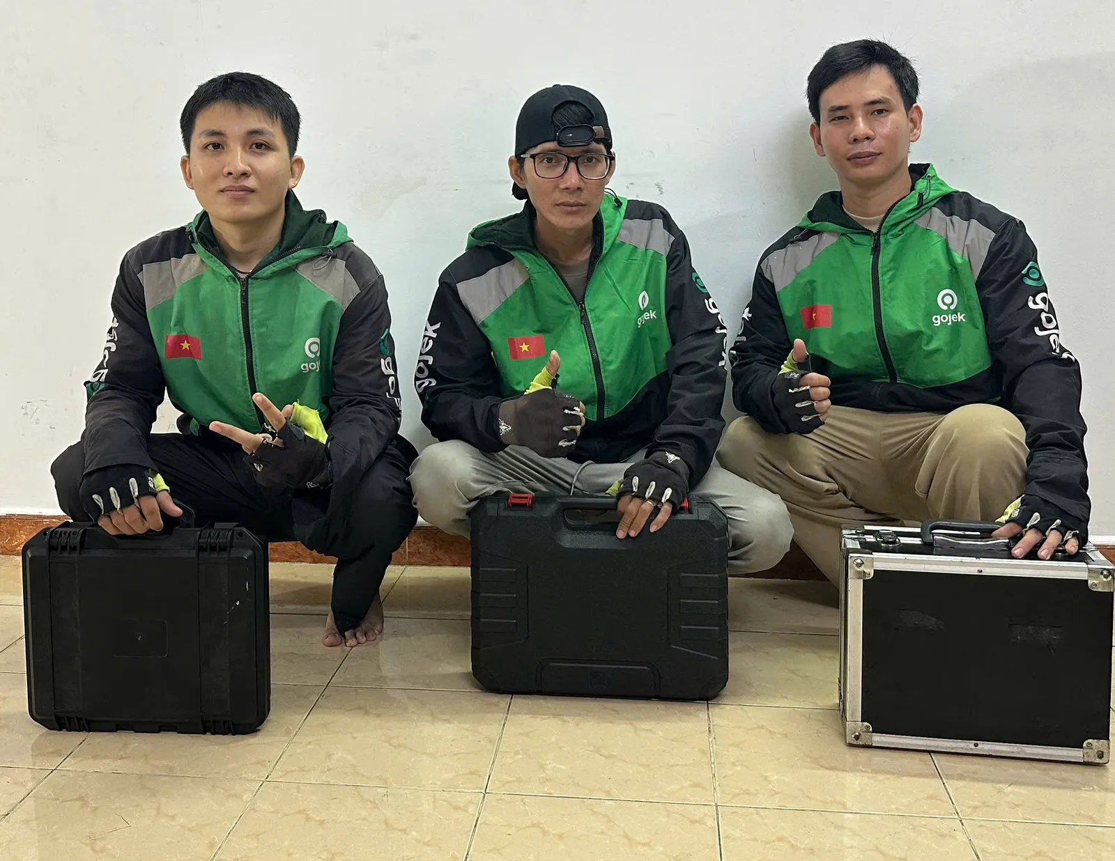 Ba thợ thay ổ khóa xe ngồi cạnh hộp đồ nghề