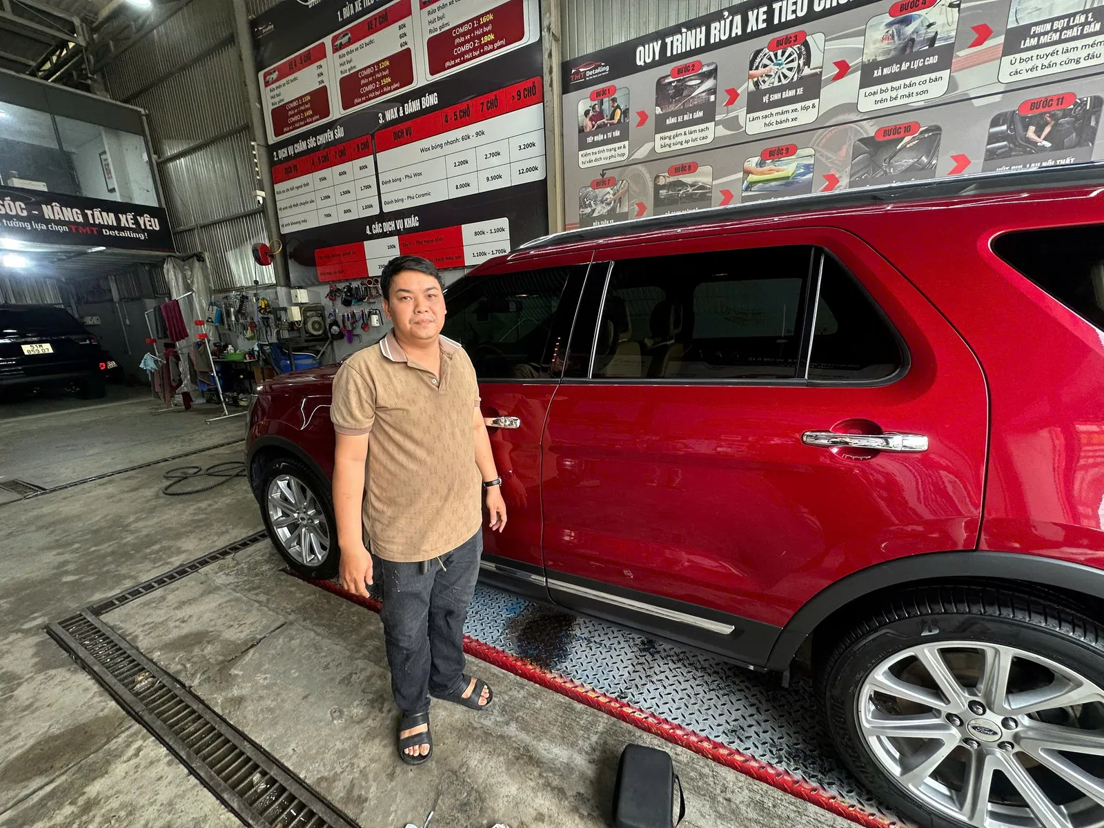 Xe SUV màu đỏ đỗ trong tiệm rửa xe, người đứng cạnh xe