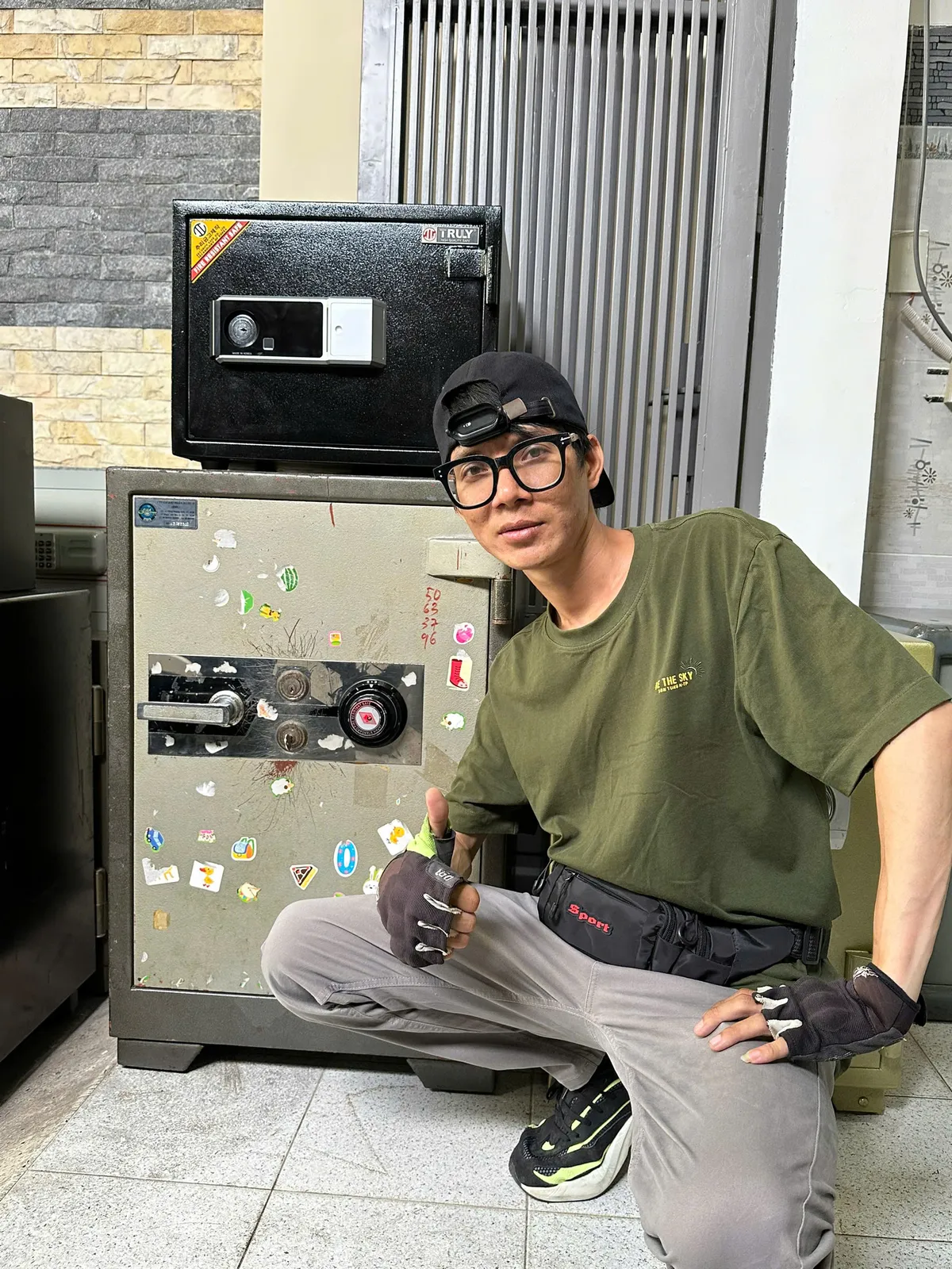 Thợ bên két sắt cơ dán nhiều sticker, phía trên có két nhỏ
