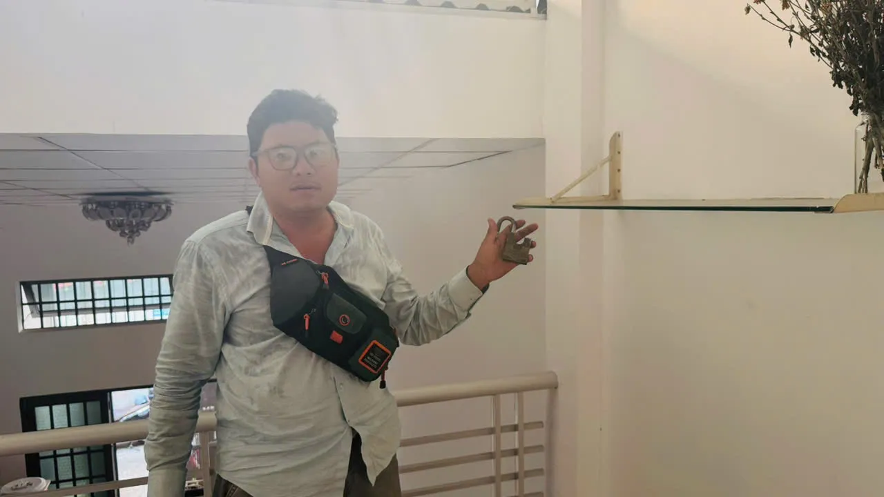 Thợ khóa cầm ổ khóa vừa thay ở chiếu nghỉ cầu thang