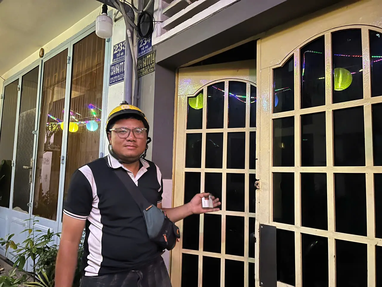 Thợ khóa đến nhà phố buổi tối, đứng trước cửa gỗ kính
