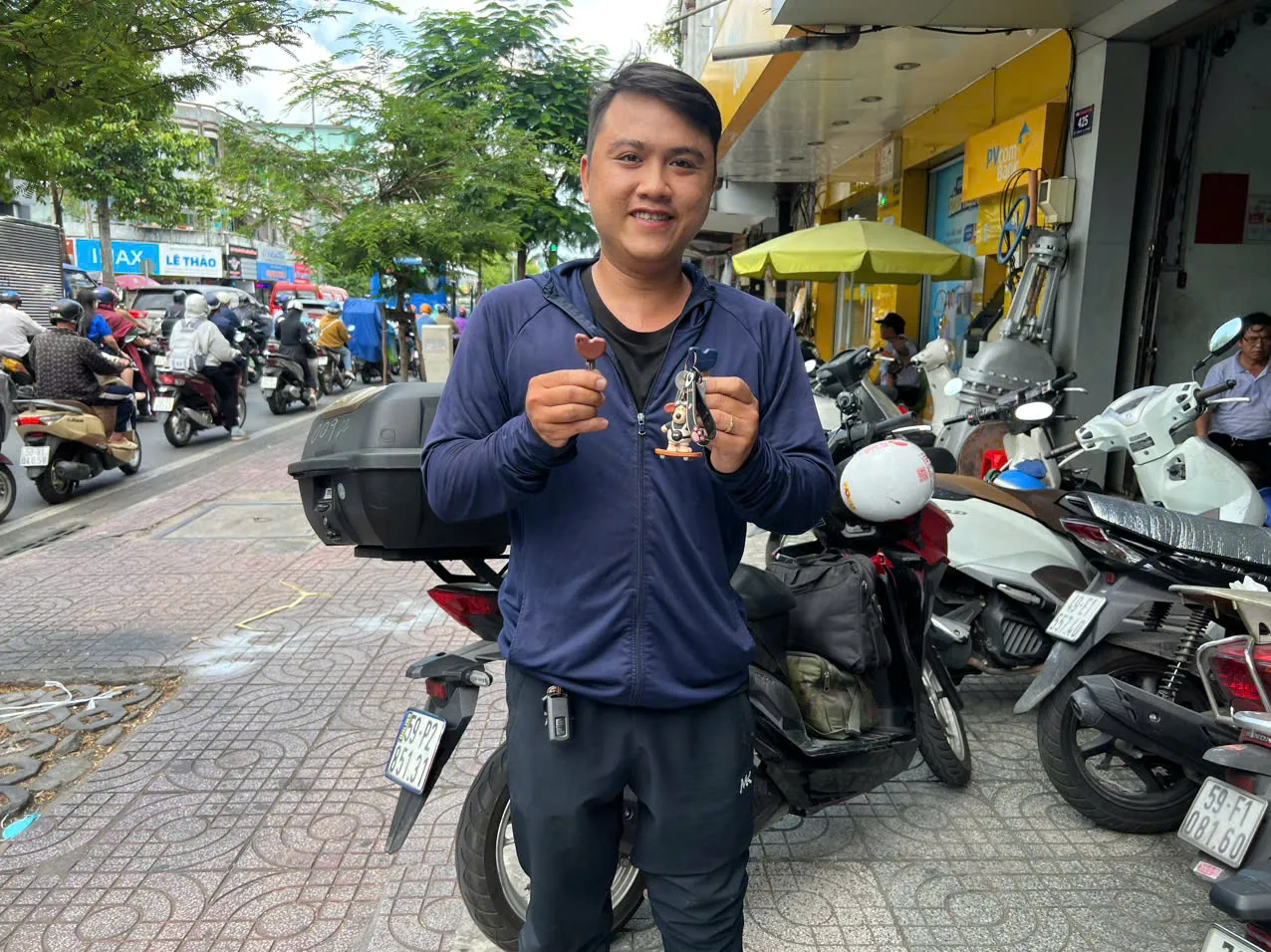 Thợ khóa xe máy cầm chìa vừa làm, đứng giữa phố