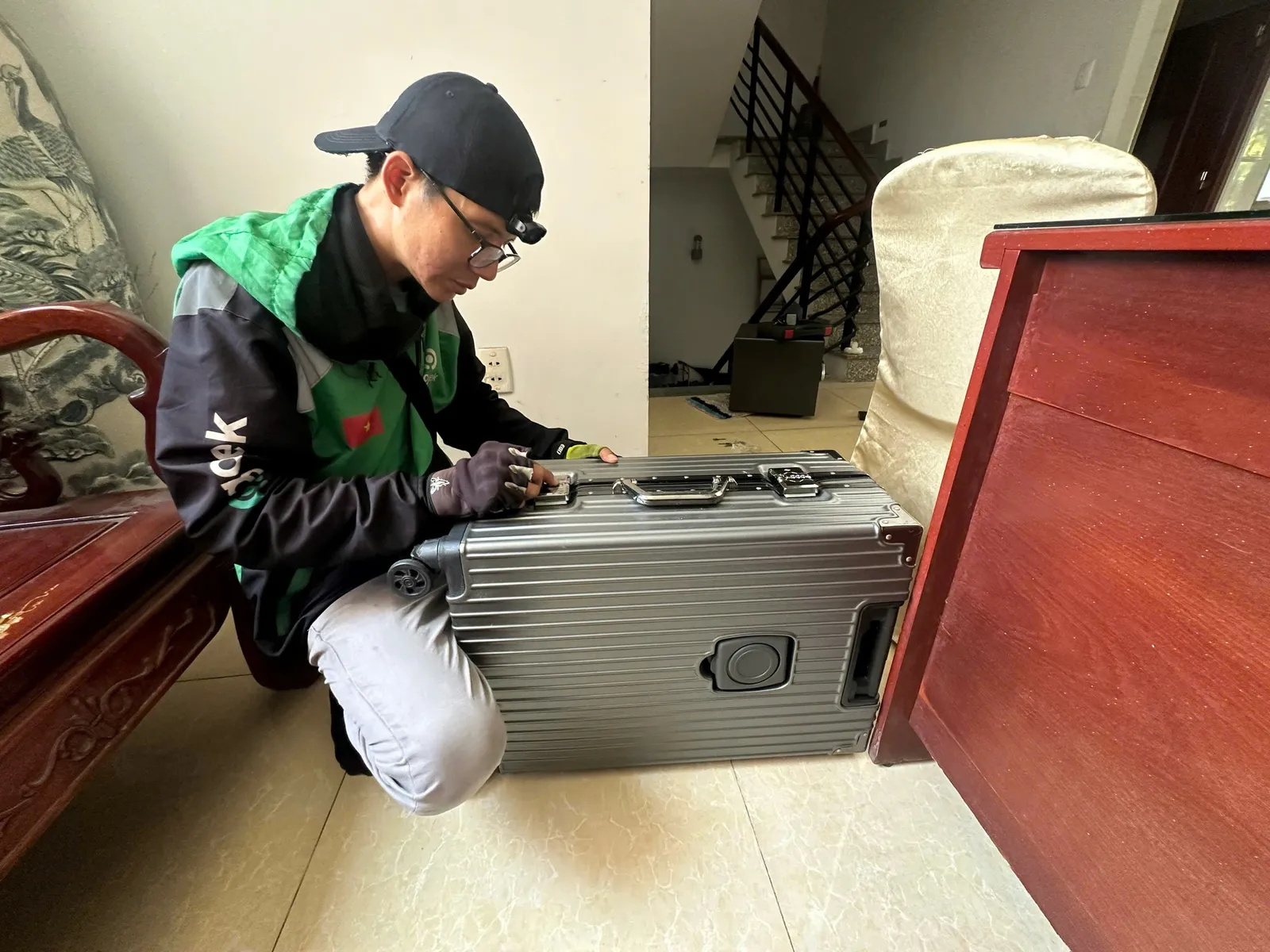 Thợ ngồi mở khóa vali nhôm cho khách tại nhà