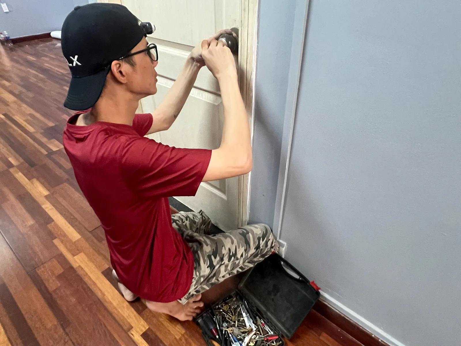 Thợ quỳ sửa khóa tay nắm tròn, sàn gỗ