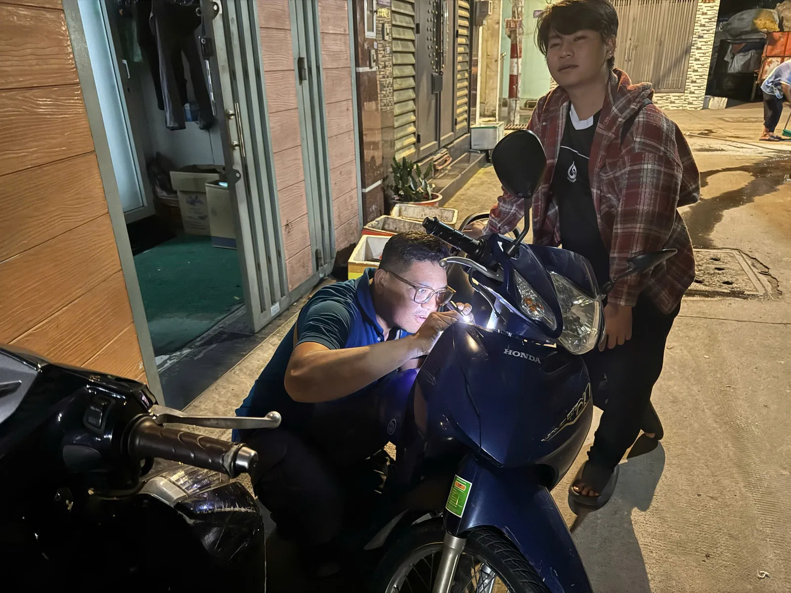 Thợ soi đèn kiểm tra ổ khóa xe số lúc ban đêm
